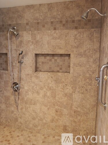 A shower area with a tile wall and a glass door.