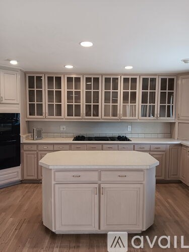 A kitchen with a white island and wooden cabinets.