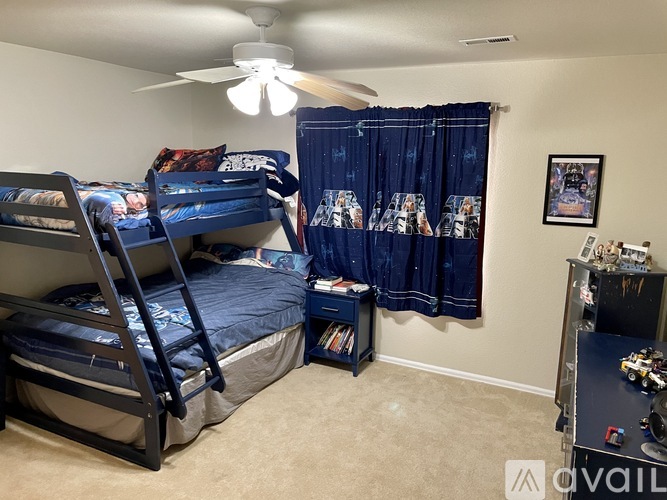 A spacious room with a carpeted floor, a ceiling fan, and a large window overlooking the beach.