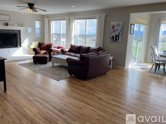 A living room with a brown leather couch and a wooden floor.
