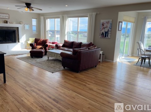A living room with a brown leather couch and a wooden floor.