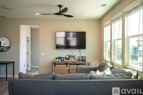 A living room with a grey couch and a flat screen TV mounted on the wall.