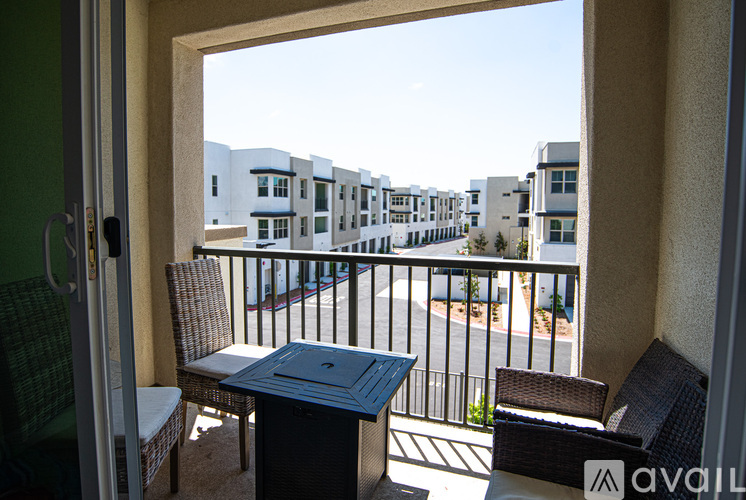 A balcony with a table and chairs overlooks a street with buildings.