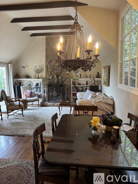 A dining room with a table set for four and a chandelier hanging from the ceiling.