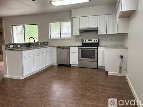 A kitchen with white cabinets and a wooden floor.