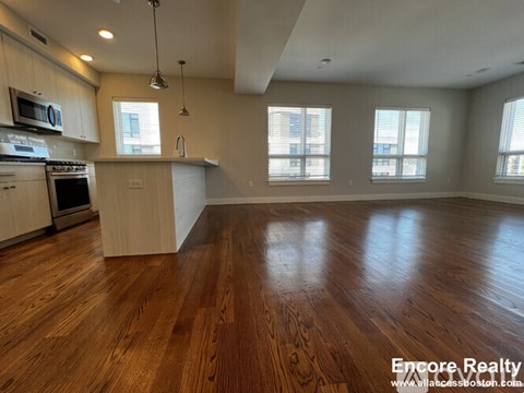 A kitchen with wooden floors and white cabinets.