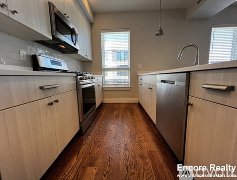 A kitchen with white cabinets and a wooden floor.