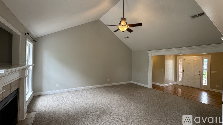 A spacious room with a fireplace on the left and a ceiling fan in the middle.