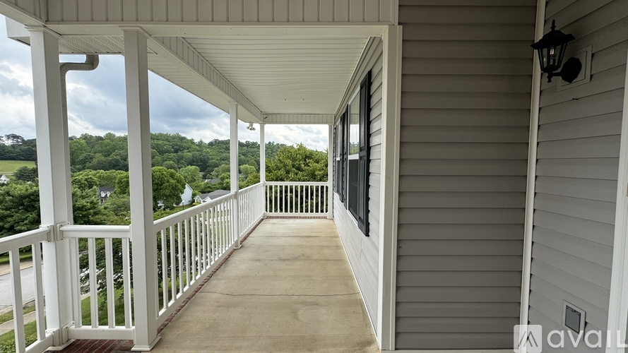 A porch with a white railing and a view of trees.