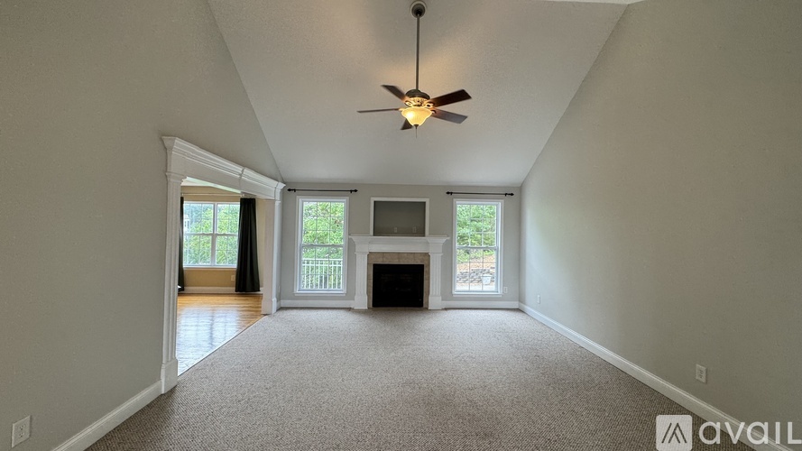 A spacious living room with a fireplace and a ceiling fan.