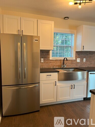 A kitchen with a stainless steel refrigerator and white cabinets.