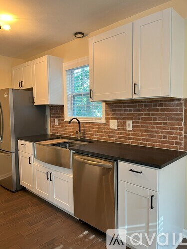 A kitchen with white cabinets and a brick wall backsplash.