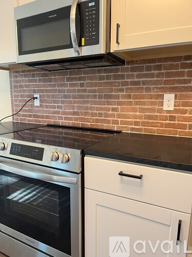 A kitchen with a brick wall and a stainless steel oven.