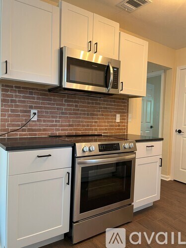 A kitchen with white cabinets and a brick wall.