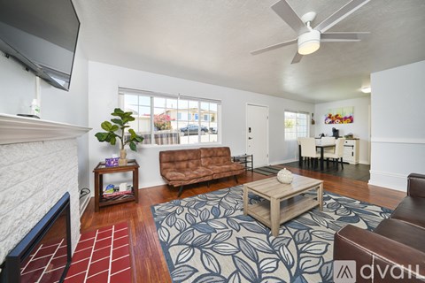 A living room with a brown couch and a blue and white rug.
