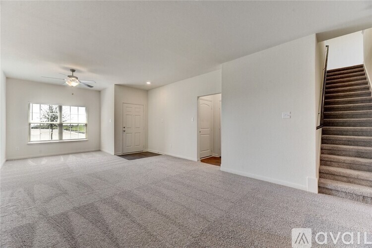 A spacious room with a staircase on the right side.