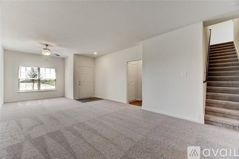 A spacious room with a staircase on the right side.