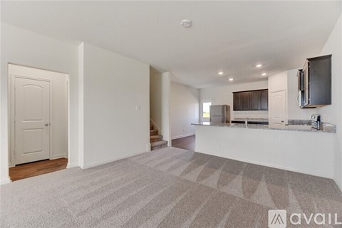 A spacious living room with a carpeted floor and a television on the wall.