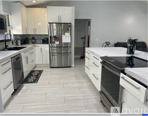 A kitchen with white cabinets and a stainless steel refrigerator.