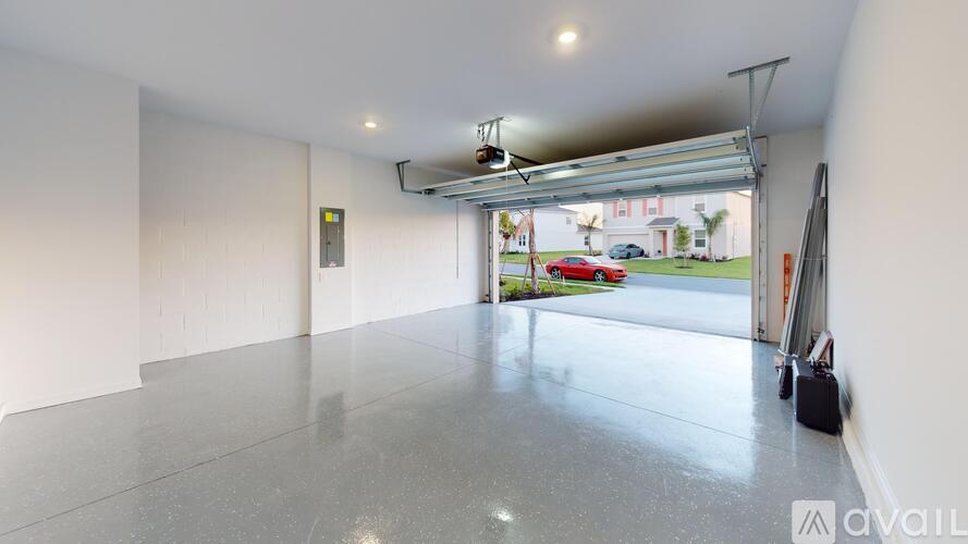 A spacious garage with a view of a red car parked outside.