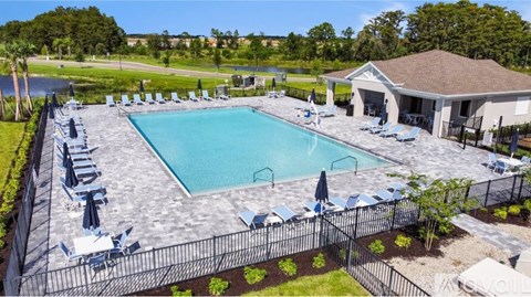 A large outdoor swimming pool surrounded by a black fence and lounge chairs.