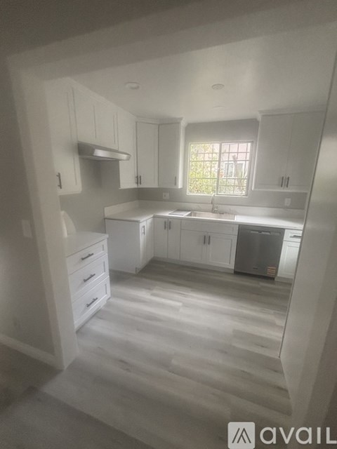 A kitchen with white cabinets and a window.