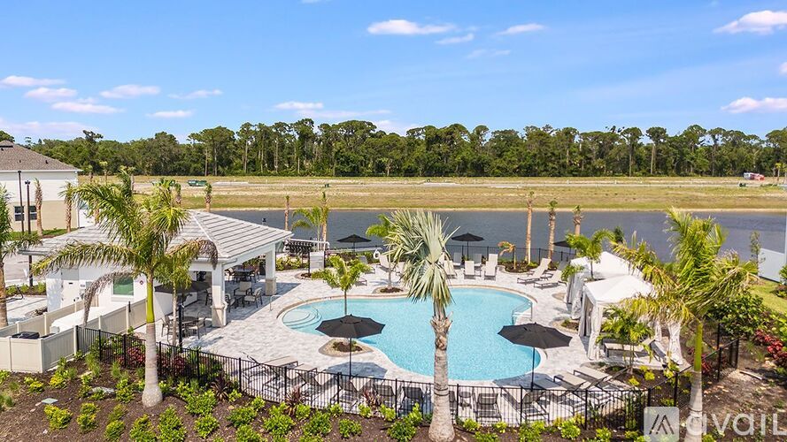 A pool surrounded by palm trees and a patio area.