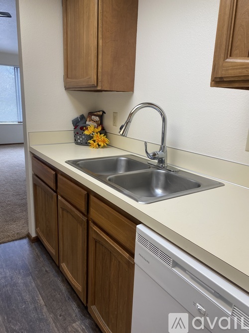 A kitchen with a white dishwasher and wooden cabinets.