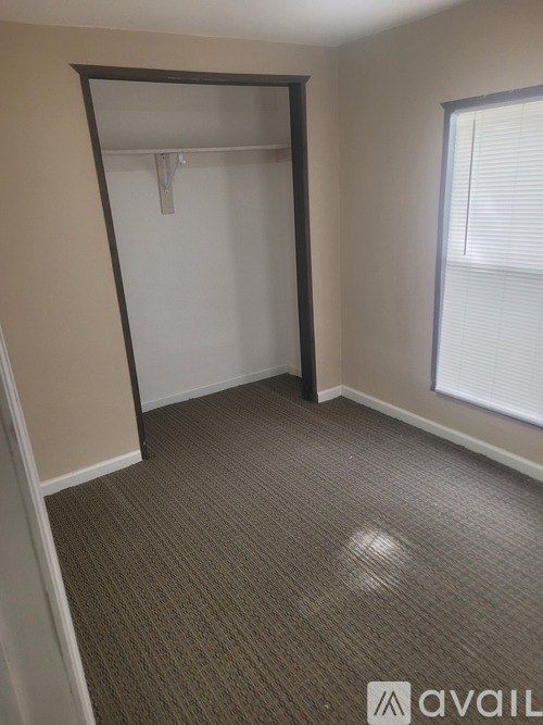 A room with a carpeted floor and a window with blinds.