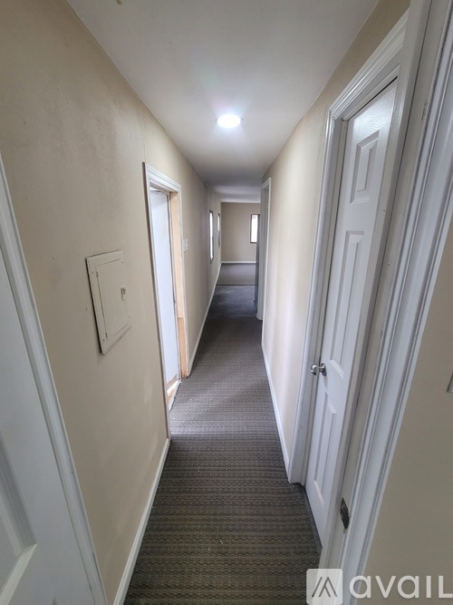 A long hallway with white doors and a carpeted floor.