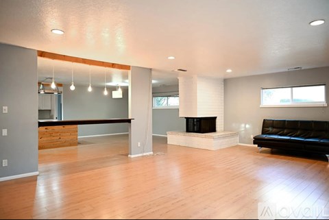 A living room with a black couch and a fireplace.