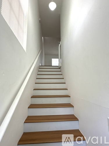 A long flight of stairs with wooden steps and white walls.