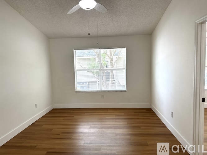 A room with wooden floors and a window with a view of a building outside.