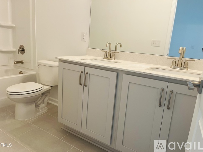 A bathroom with a toilet, sink, and cabinets.