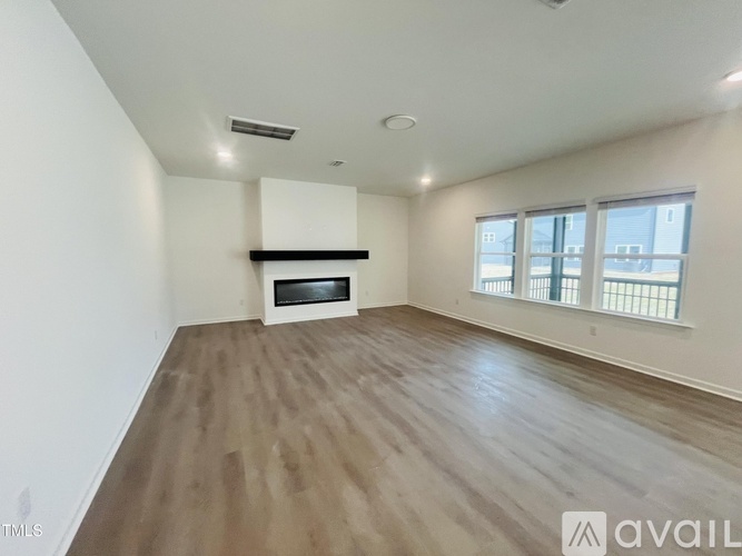 A spacious room with wooden flooring and a large window.
