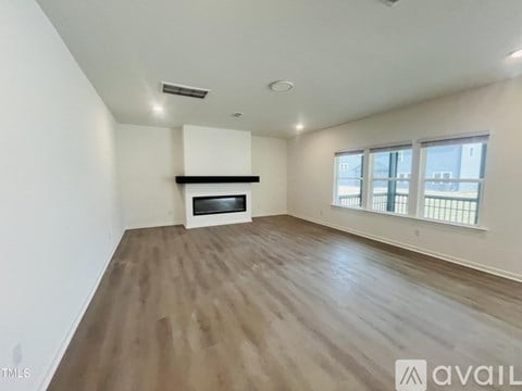 A spacious room with wooden flooring and a large window.