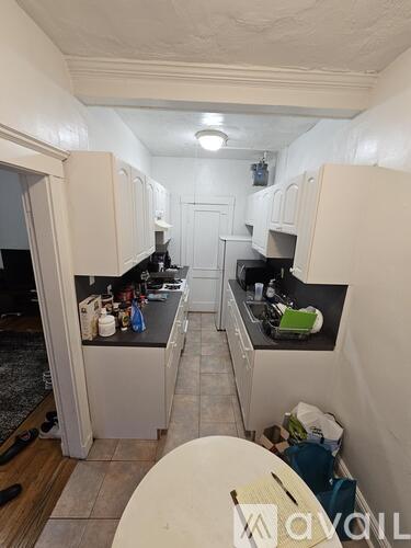 A kitchen with white cabinets and a black countertop.