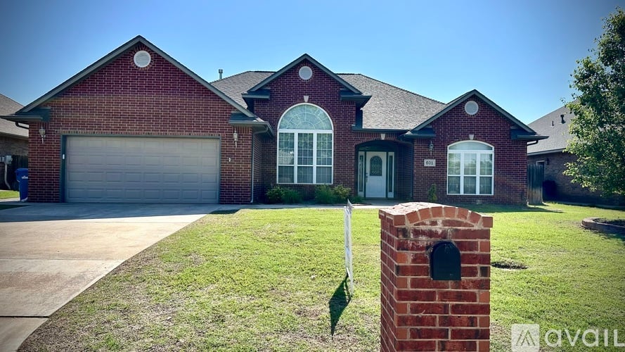 A red brick house with a white sign in front.