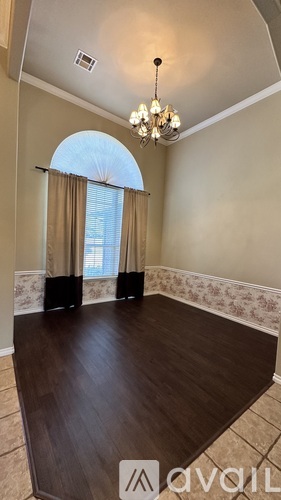 A room with a chandelier and a window with curtains.