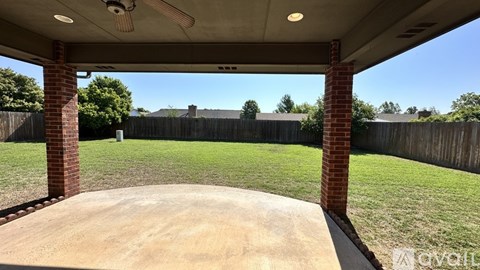 A covered patio area with a concrete floor and brick pillars.