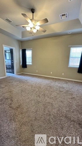 A room with a ceiling fan and carpeted floor.