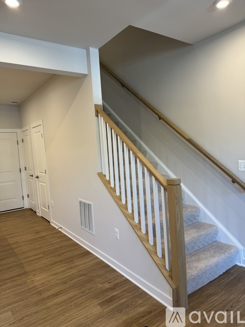 A staircase with wooden railings and a beige carpeted runner.