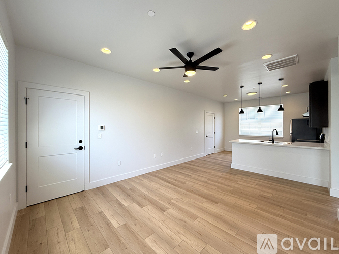 A spacious room with wooden flooring and a ceiling fan.