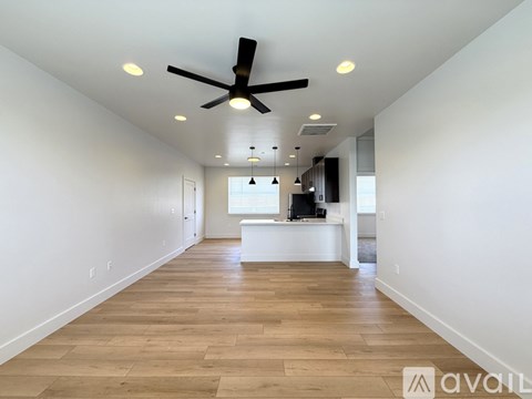 A spacious room with a ceiling fan and wooden flooring.