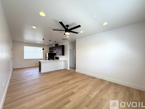 A spacious room with a ceiling fan and wooden flooring.