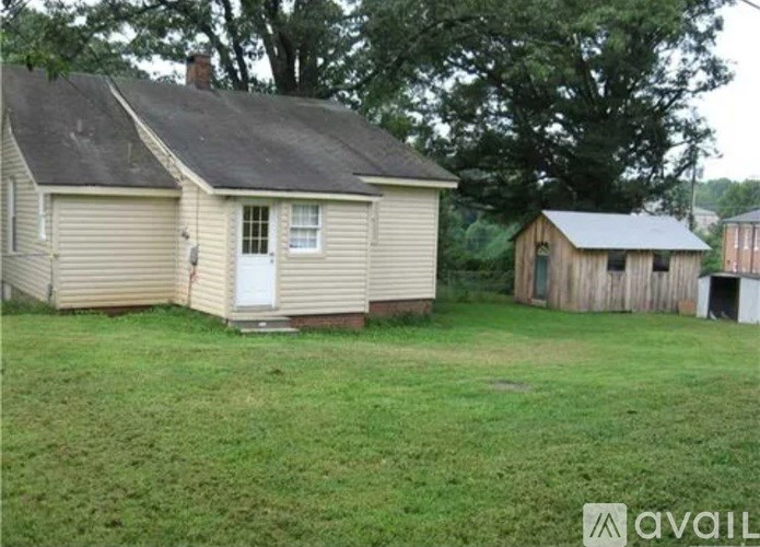 A house with a white door and a shed in the yard.
