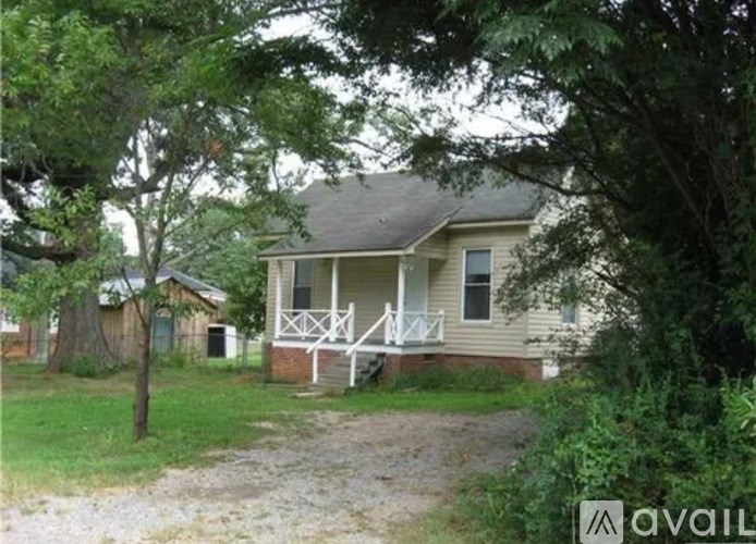 A house with a porch and a tree in front of it.