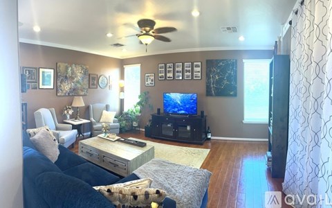 A living room with a black couch and a television.