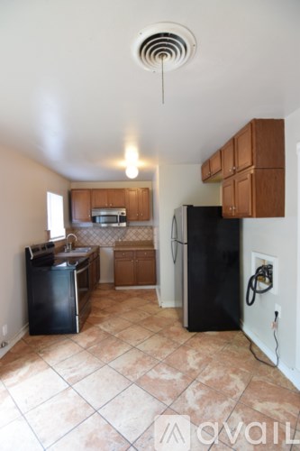 A kitchen with black appliances and brown cabinets.