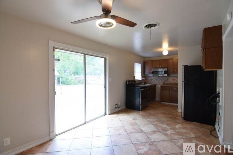 A kitchen area with a black refrigerator and a ceiling fan.